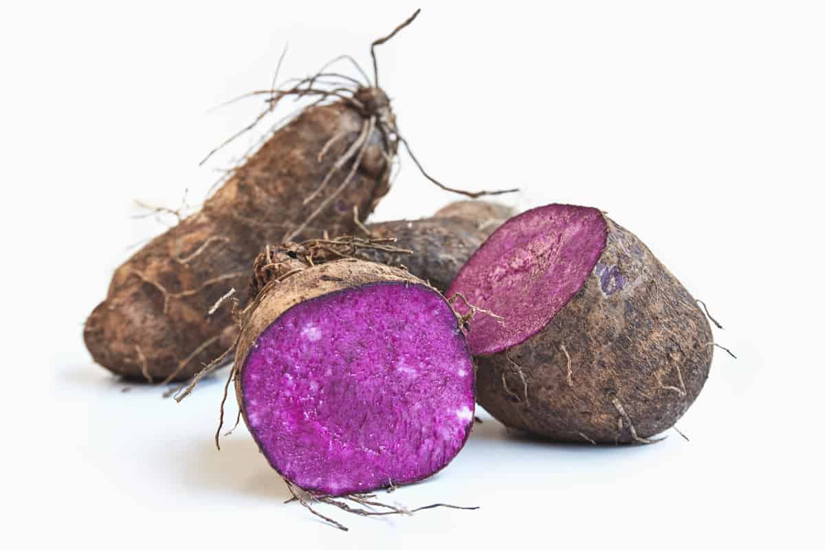 Whole ube purple yam, halved to show vibrant violet flesh